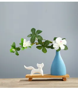 Detail view of modern blue ceramic vase set with elegant white fox figurine on a wooden stand