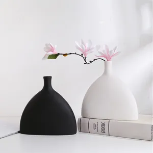 Detailweergave van moderne minimalistische keramische vazen in zwart en wit met bloemen