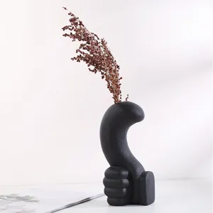 Detail view showing the matte texture of a black ceramic thumbs-up hand-shaped vase