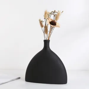 Detailweergave van een moderne zwarte mat keramische vaas met elegante droogbloemen