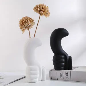 Close-up detail of modern minimalist hand-shaped ceramic vases in black and white finish