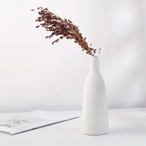 Vase minimaliste en céramique blanche avec plantes séchées dans une scène de vie