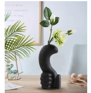 Modern black ceramic thumbs-up vase with matte finish in minimalist home setting