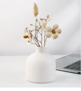 Gros plan d'un vase en céramique blanc minimaliste avec fleurs séchées