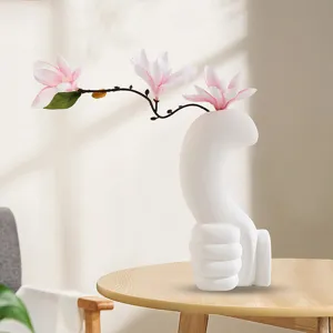 Detailed view of a unique white ceramic thumbs-up gesture vase on a wooden table