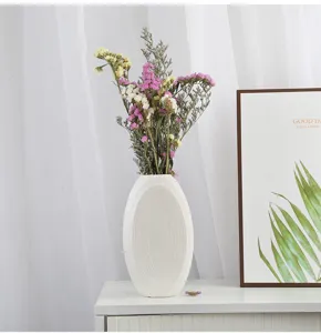 Close-up view of minimalist matte white ceramic vase in a cozy Nordic home setting
