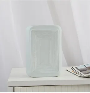 Detailed view of a matte light blue ceramic vase with concentric rectangular grooves.