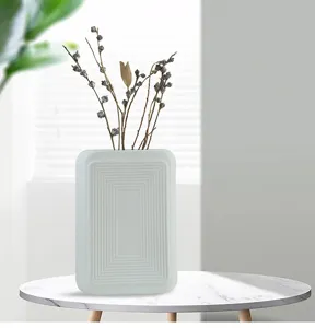 Minimalist matte white ceramic vase with geometric rectangular texture on table