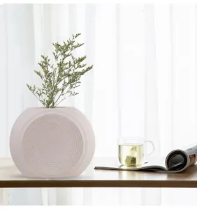 Detailed view of cream matte ceramic vase with concentric ring pattern on wooden table