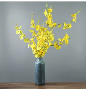 Dettaglio di un vaso in ceramica blu rustica con orchidee gialle su base in legno