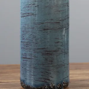 Primo piano di un vaso in ceramica rustica craquelé con glassa blu-grigia testurizzata.