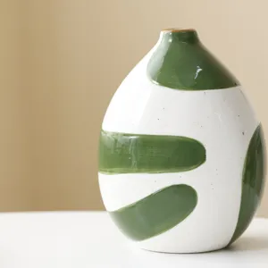 Close-up of hand-painted ceramic vase with green brushstroke patterns