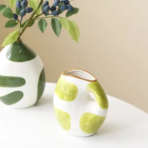 Detailed shot of a hand-painted wabi-sabi ceramic vase with light green dots and handle