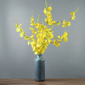 Vaso vintage in ceramica blu craquelé con orchidee gialle su tavolo di legno