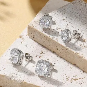 Primer plano de pendientes brillantes de circonita sobre expositores de piedra texturizada.