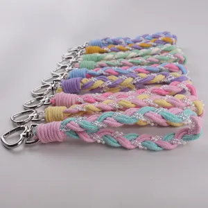 Detailaufnahme der bunten geflochtenen Handgelenkschlaufe mit Perlen und Herzverschluss.