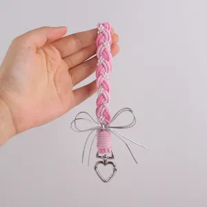 Detail van roze gevlochten telefoonkoord met witte kralen, zilveren strik en hart sluiting.