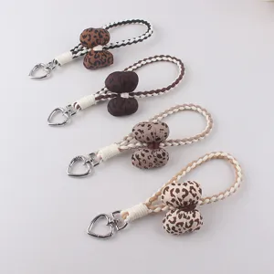 Cute leopard print braided phone charm and keychain with heart clasp, stylish bag accessory.