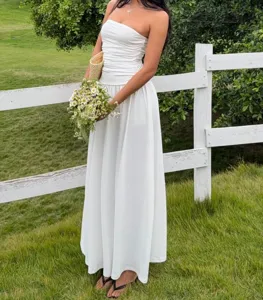 Elegant white ruched tube top maxi dress shown in a sunny outdoor summer field setting