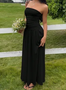 Elegant black strapless maxi dress with ruffled waist in a summer outdoor setting
