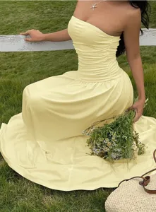 Elegant yellow strapless ruched maxi dress with flared skirt shown in a summer field setting