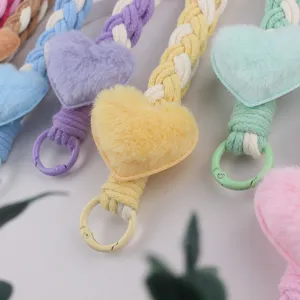 Close-up detail of colorful braided rope keychain featuring soft plush heart pendant charm.