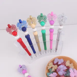 Kleurrijke DIY kraal balpennen met glitter siliconen strikjes op transparante display stand.
