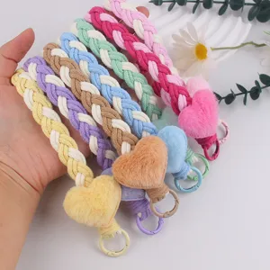 Close-up detail of colorful braided plush heart phone lanyard and cute bag charm keychain.