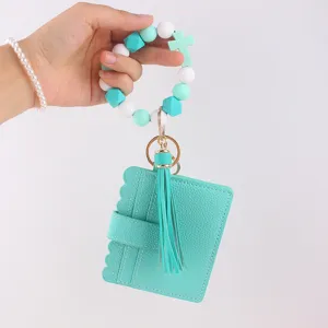 Detailed view of mint green silicone bead wristlet keychain with card holder and tassel.