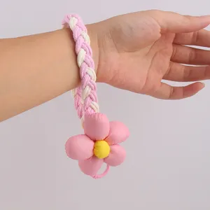 Detailaufnahme eines süßen rosa-weiß geflochtenen Handygelenkriemens mit Stoffblume.