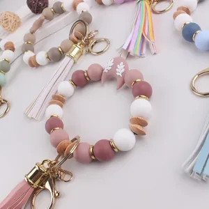 Detalle de llavero de cuentas de silicona y madera, abalorio de luna coloridas y borla elegante.