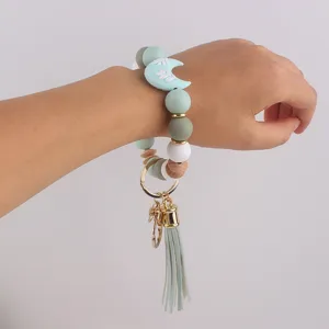 Detalle de pulsera llavero de cuentas de silicona con colgante de luna y borla.