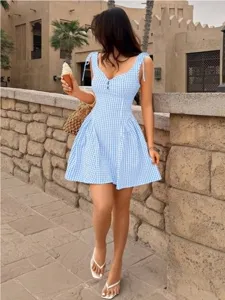 Charming blue and white gingham tie-strap mini dress with a sweet flared skirt for summer.