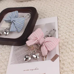 Detailed close-up of cute plaid fabric bow keychains with silver heart pendants and hooks.