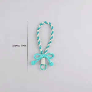 Laccetto per telefono intrecciato a mano con ciondolo a fiocco, accessorio elegante e colorato.