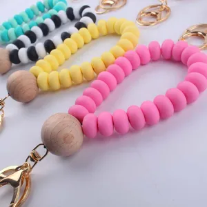 Silicone beaded keychain wristlet with large wooden bead and gold metal hardware for daily use.