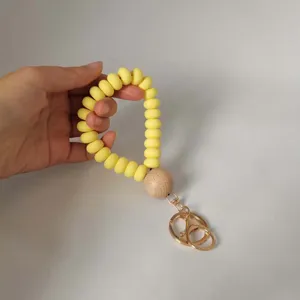Silicone beaded bracelet keychain with wooden bead and gold hardware detail close-up.
