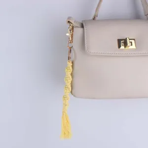 Handmade yellow macrame cotton keychain with golden metal ring and stylish tassel design detail.