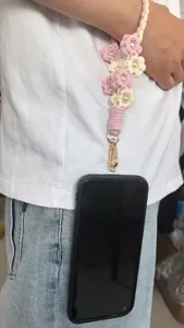 Handmade woven pearl flower phone strap detail, cute pink candy color hanging cord display.