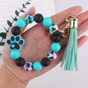Silicone dog paw bead keychain detail view, featuring mint green tassel and metal clasp.