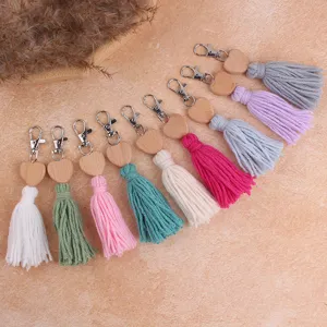 Close-up detail of bohemian style cotton tassel keychain with wooden heart and metal clasp.