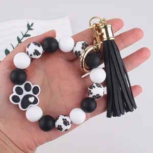 Silicone dog paw print beaded keychain bracelet detail view with black tassel and gold hardware.