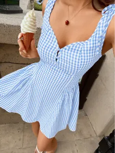 Detail of a blue and white gingham mini dress with a sweetheart neckline and shoulder ties.