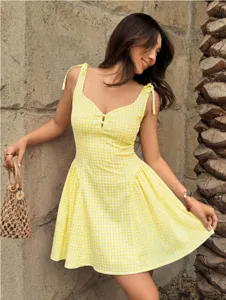 Detailed view of sweet yellow gingham camisole dress featuring bow straps and button decor