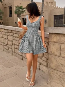 Detailed shot showing the fit of a black and white gingham strap dress in a sunny setting.