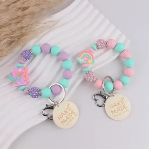 Silicone beaded keychain with handmade wooden tag and cute cartoon charms detail view.