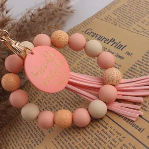 Bracelet porte-clés en perles de silicone avec étiquette en bois et pompon en cuir.