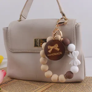Silicone bead keychain with wooden bow charm, handmade style bag accessory and keyring pendant.