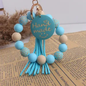 Porte-clés bracelet en perles de silicone avec pendentif en bois et gland en cuir élégant.