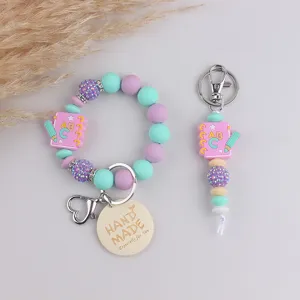 Silicone beaded bracelet keychain set with cute notebook charm and handmade wooden tag pendant.